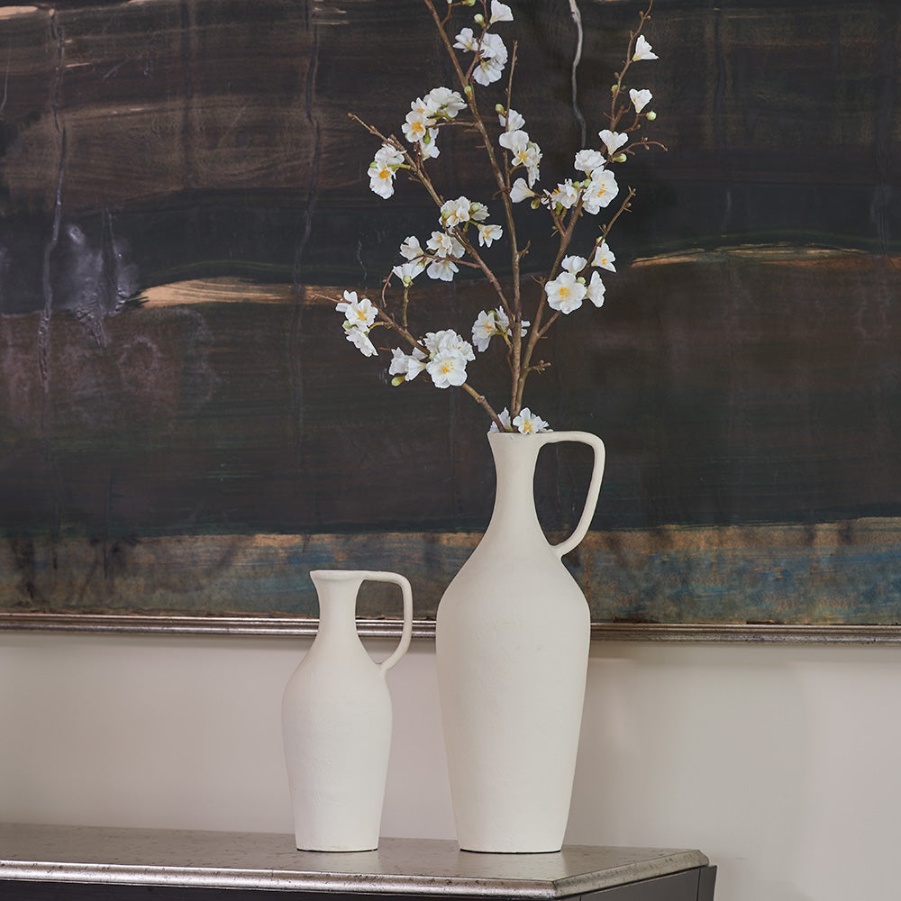 Close up of matching creme pitchers with olive branch