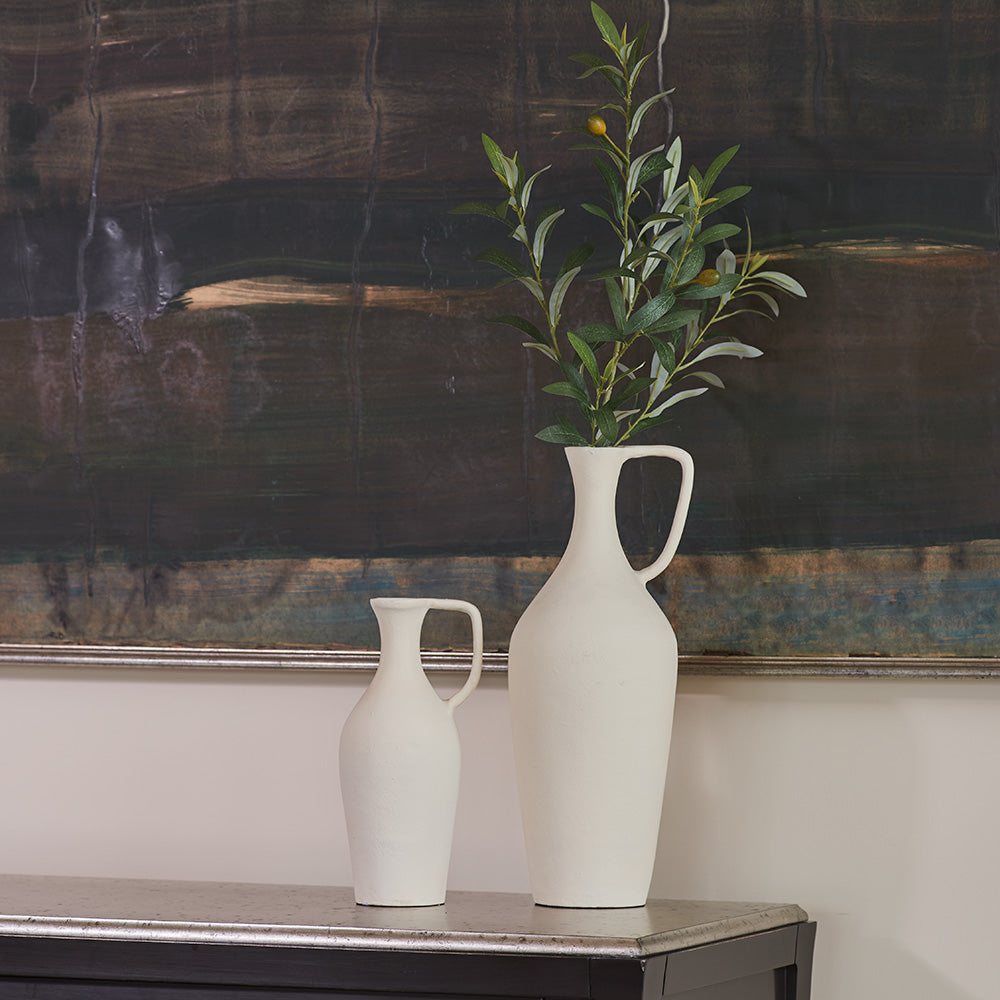 Close up of matching creme pitchers with green branch